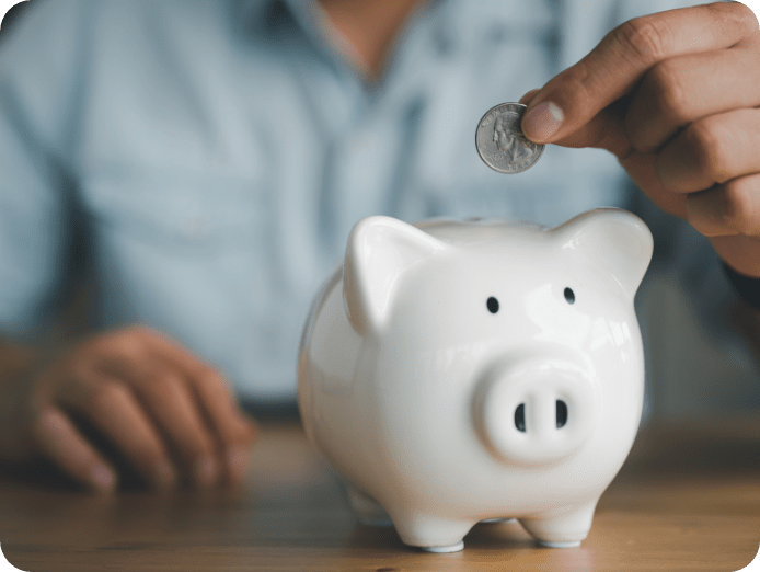 A person placing a coin in a white Piggy bank