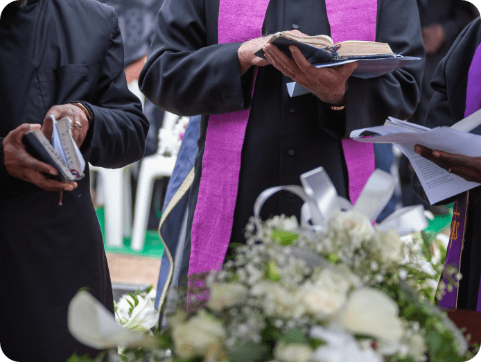 Priests at a burial ceremony holding open bibles