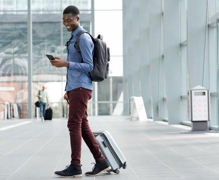 Young man walking in an airport while on his phone